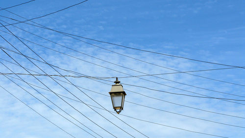 Low angle view of power lines against blue sky