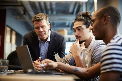 Male entrepreneur giving presentation over laptop at desk in creative office