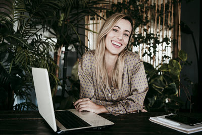 Portrait of smiling young woman using smart phone at table