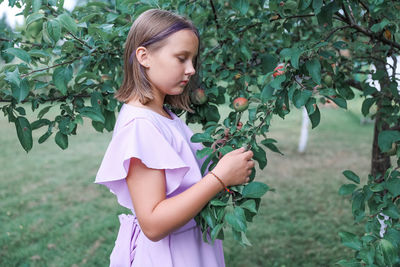 Portrait of young woman standing against plants