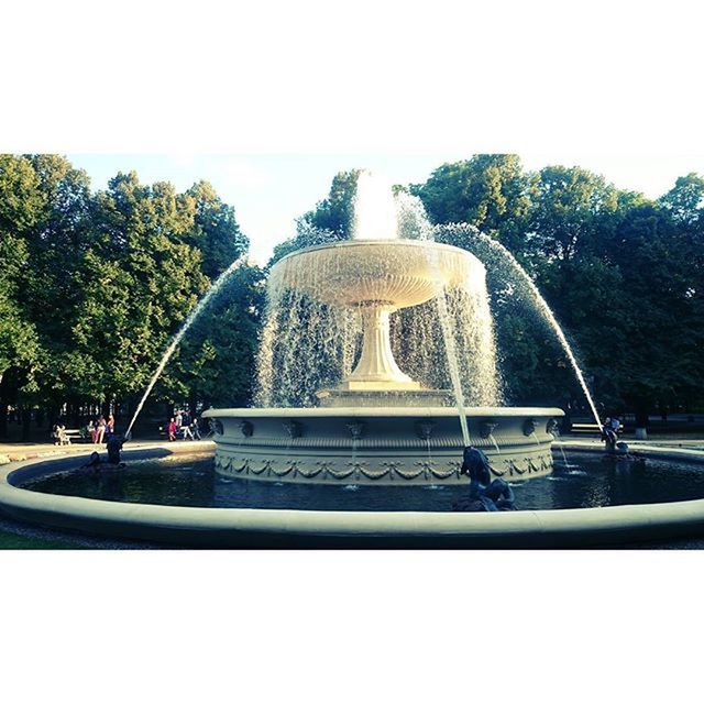 tree, clear sky, fountain, park - man made space, sky, incidental people, day, sunlight, built structure, outdoors, sculpture, travel destinations, travel, growth, transportation, nature, statue, architecture, auto post production filter, building exterior