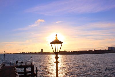 Silhouette built structure by sea against sky during sunset