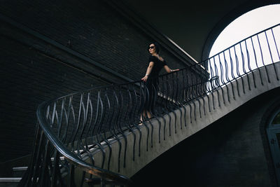 A pretty charming middle-aged woman in a black dress and sunglasses strolls through in the stairs