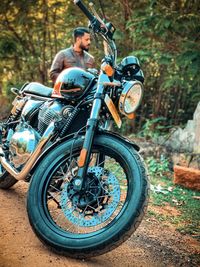 Man standing by motorcycle against trees