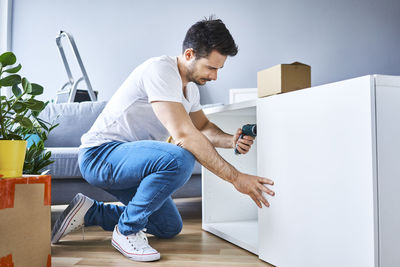 Man assembling a bookshelf in new apartment