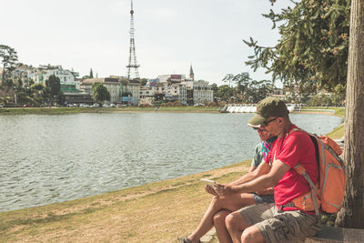 Man sitting by river against trees