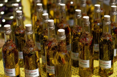 Close-up of olive oil with ingredients in glass bottles on table