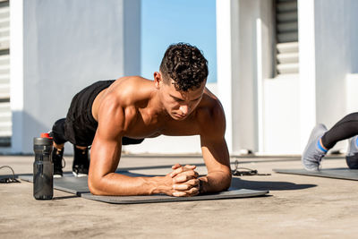 Full length of shirtless man exercising outdoors