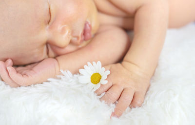 Cute baby with flower sleeping on bed at home