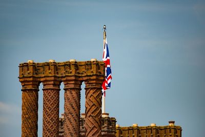 Low angle view of flag on building against sky