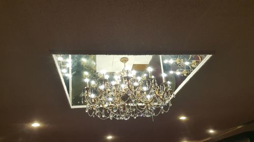 Low angle view of illuminated chandelier hanging on ceiling