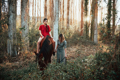 Woman sitting on horse while standing with friend
