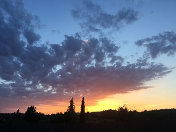 Silhouette landscape against dramatic sky during sunset