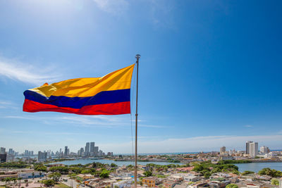 Flag against buildings in city against blue sky