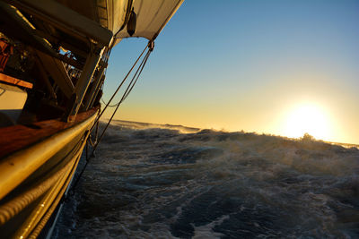 Boat splashing in sea against clear sky during sunset