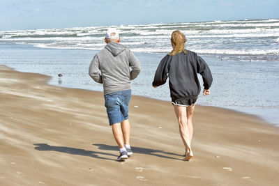 Rear view of couple walking at beach