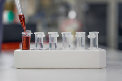 The lab technician injects the red liquid into a microtiter plate