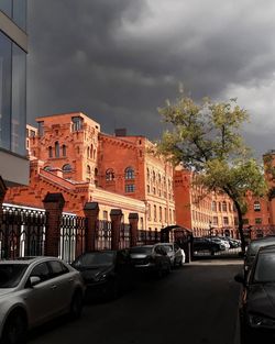 Cars on street by buildings in city against sky
