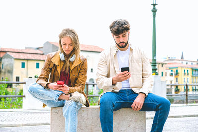 Couple using mobile phone while sitting outdoors