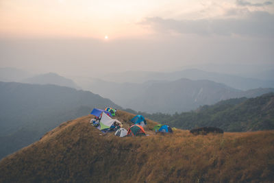 People on mountain range against sky during sunset