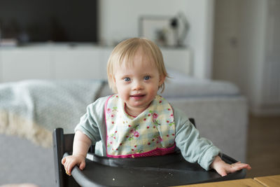 Toddler with down syndrome sitting on high chair