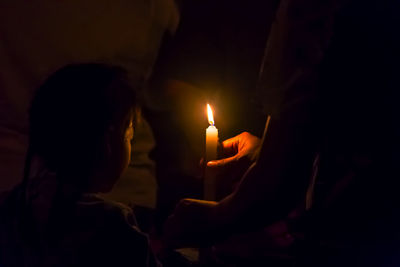 Cropped hand holding candle in darkroom