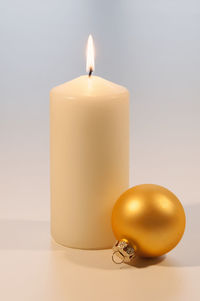 Close-up of illuminated candle over white background