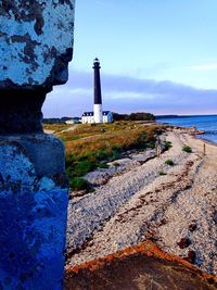 Lighthouse by sea against blue sky