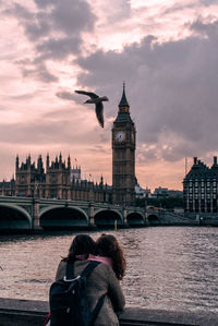 Mother and daughter by thames river against big ben during sunset