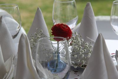 Close-up of wineglasses with rose and napkins on table