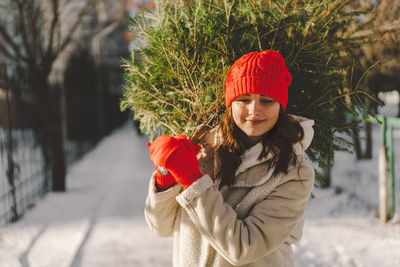 A beautiful girl in a red hat carries a christmas tree. christmas tree