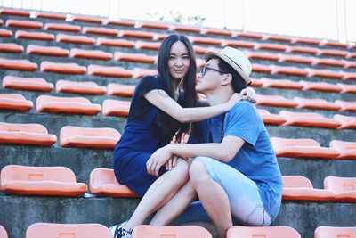 Portrait of girlfriend sitting with boyfriend at stadium