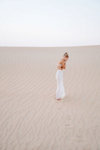 Woman in the sand dune hiding her face with hands