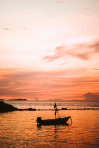 Silhouette man in sea against sky during sunset