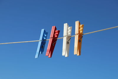 Low angle view of flags hanging against blue sky