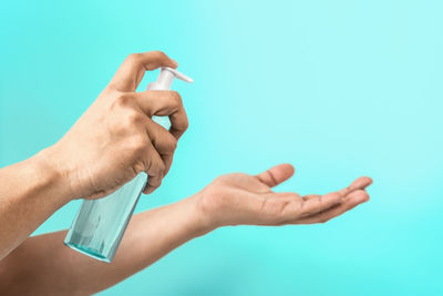 Close-up of hand holding eyeglasses against blue background