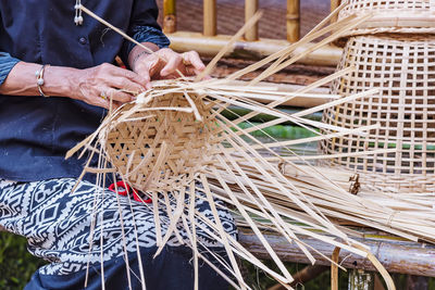 Midsection of woman making wicker basket