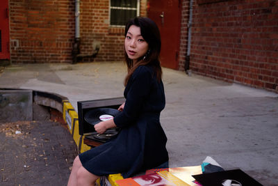 Full length of woman sitting against wall