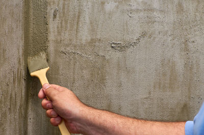 Close-up of man holding hands against wall