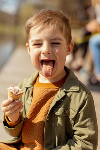 Little adorable boy sitting outdoors and eating ice cream. lake, water and sunny weather