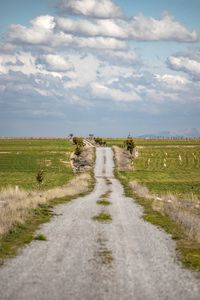 People walking on dirt road against sky