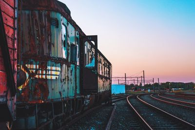 Train on railroad tracks against clear sky during sunset