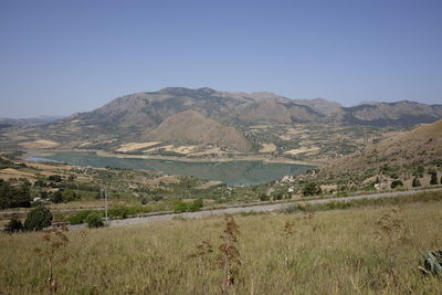 Scenic view of field and mountains against clear sky