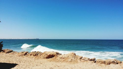 Scenic view of beach against clear blue sky