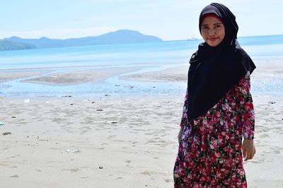 Woman standing at beach against sky