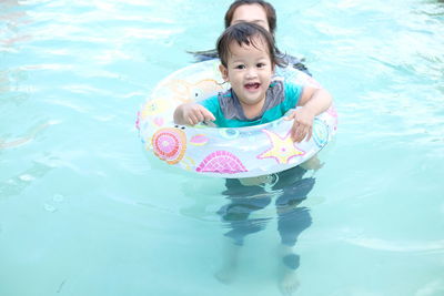 Portrait of baby girl with inflatable ring swimming in pool