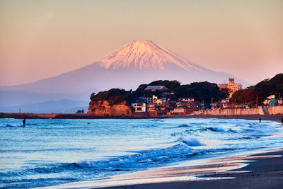 Scenic view of sea and snowcapped mountain against clear sky in the morning