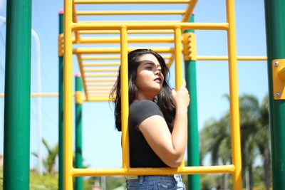 Young woman looking away while standing on playground
