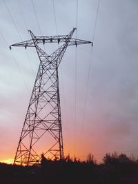 Low angle view of silhouette electricity pylon on field against sky