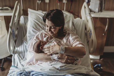 Mid view of mother in hospital bed looking at newborn son